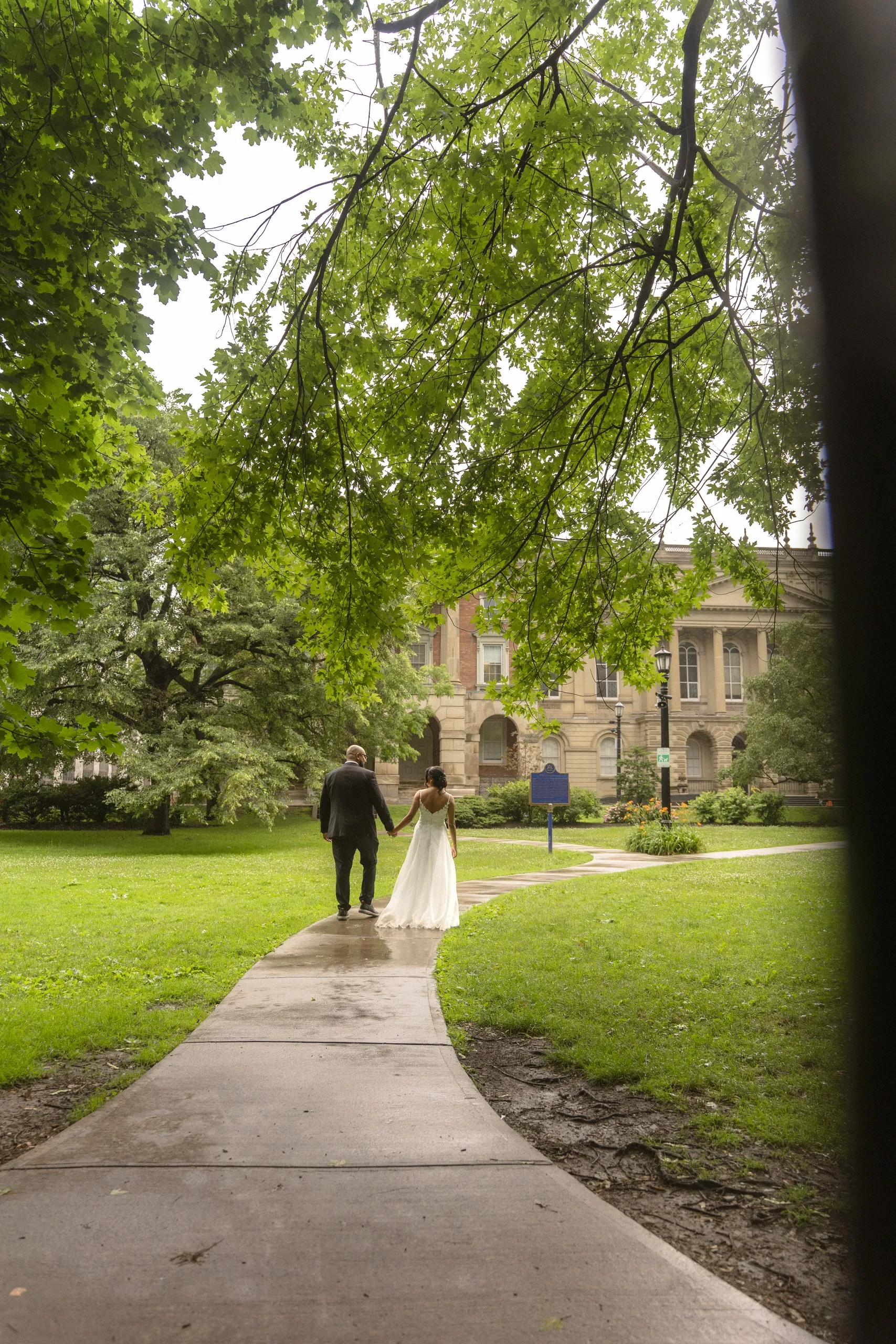 Bride and groom walk away down the Osgoode Hall garden path, by AD Photography
