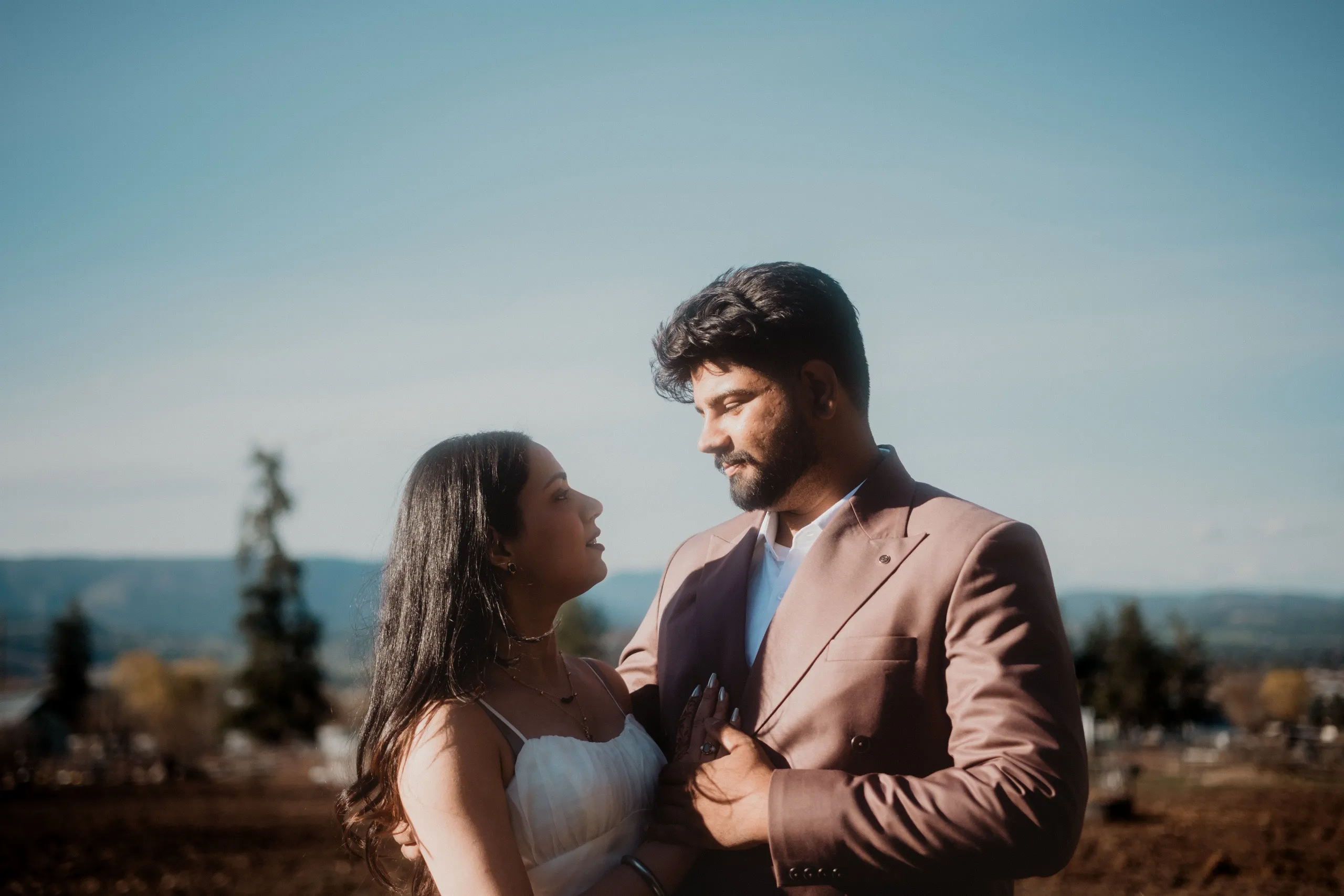 Mehak resting a hand on Kamal's lapel with the valley opening out behind them, by AD Photography