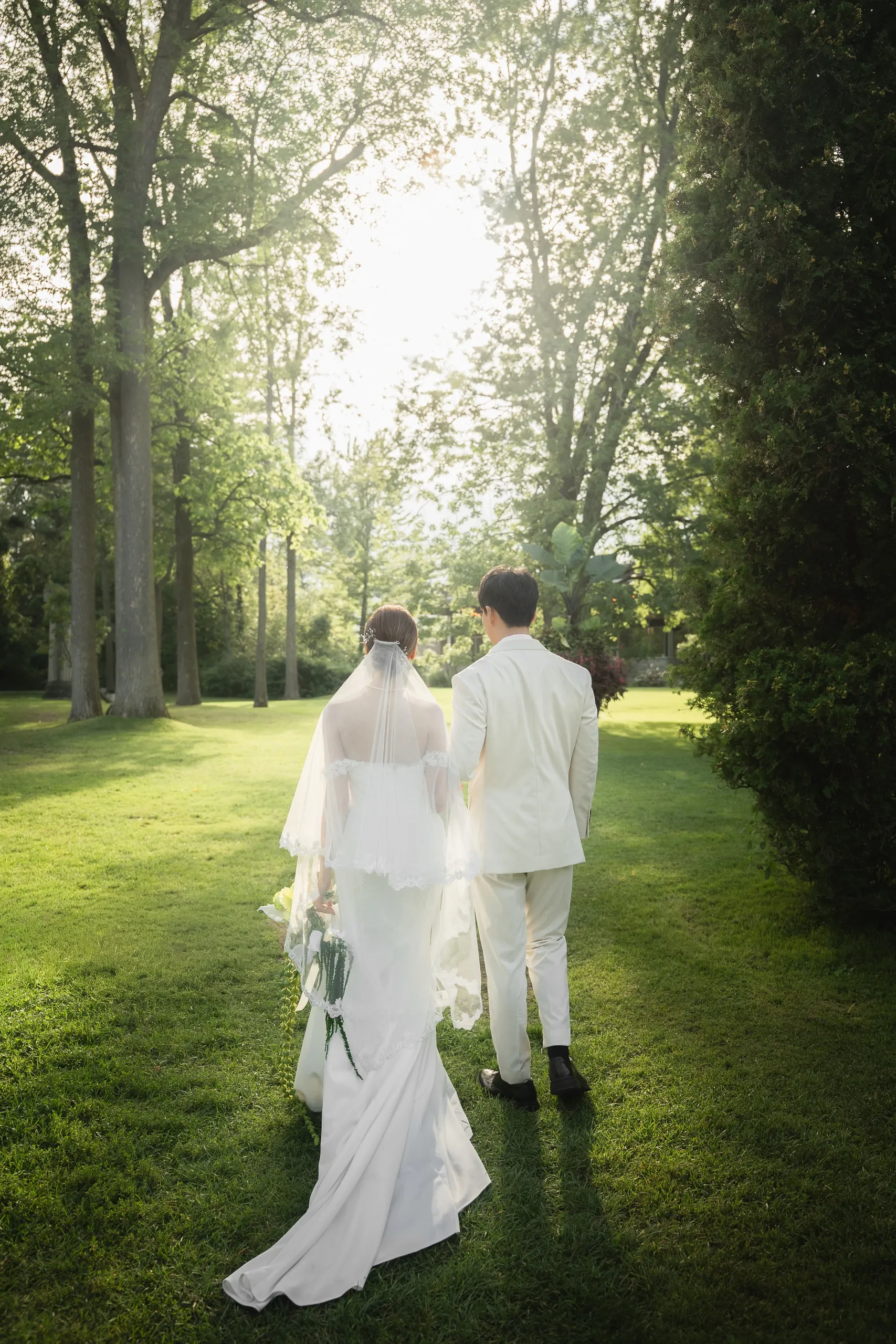 Josie and Nelson walking away across the backlit lawn in a grainy film look, by AD Photography