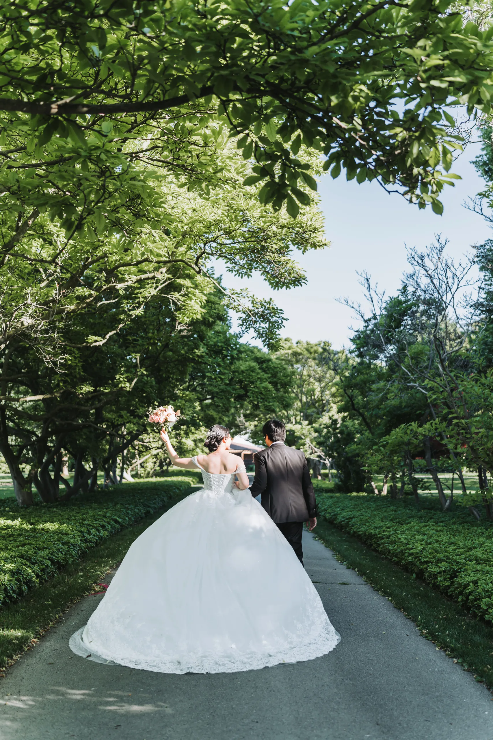 Karen and Micheal walking with their foreheads close, framed through garden foliage in Niagara Falls, by AD Photography