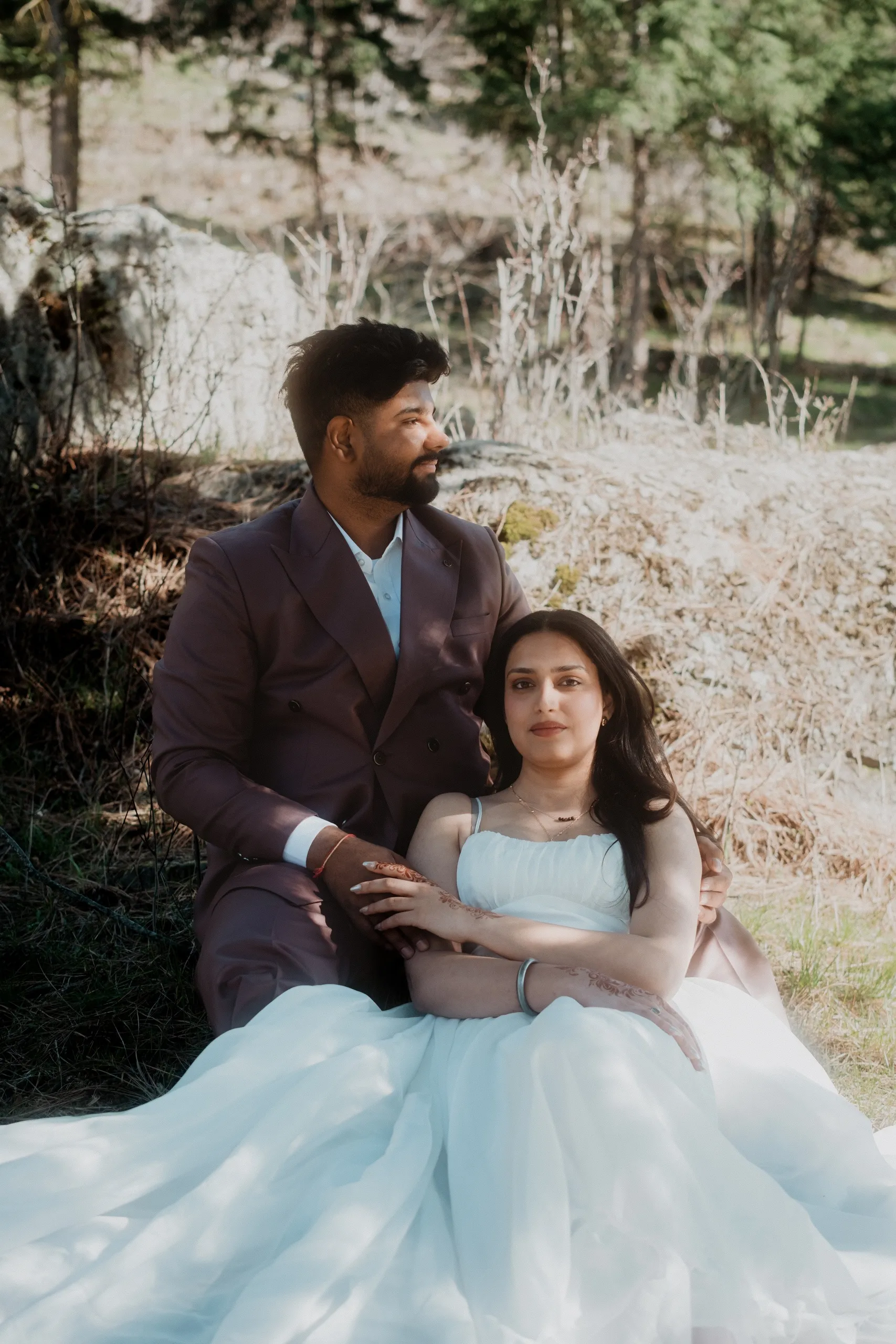 Mehak and Kamal resting on a rock, her tulle gown pooling across the ground, by AD Photography