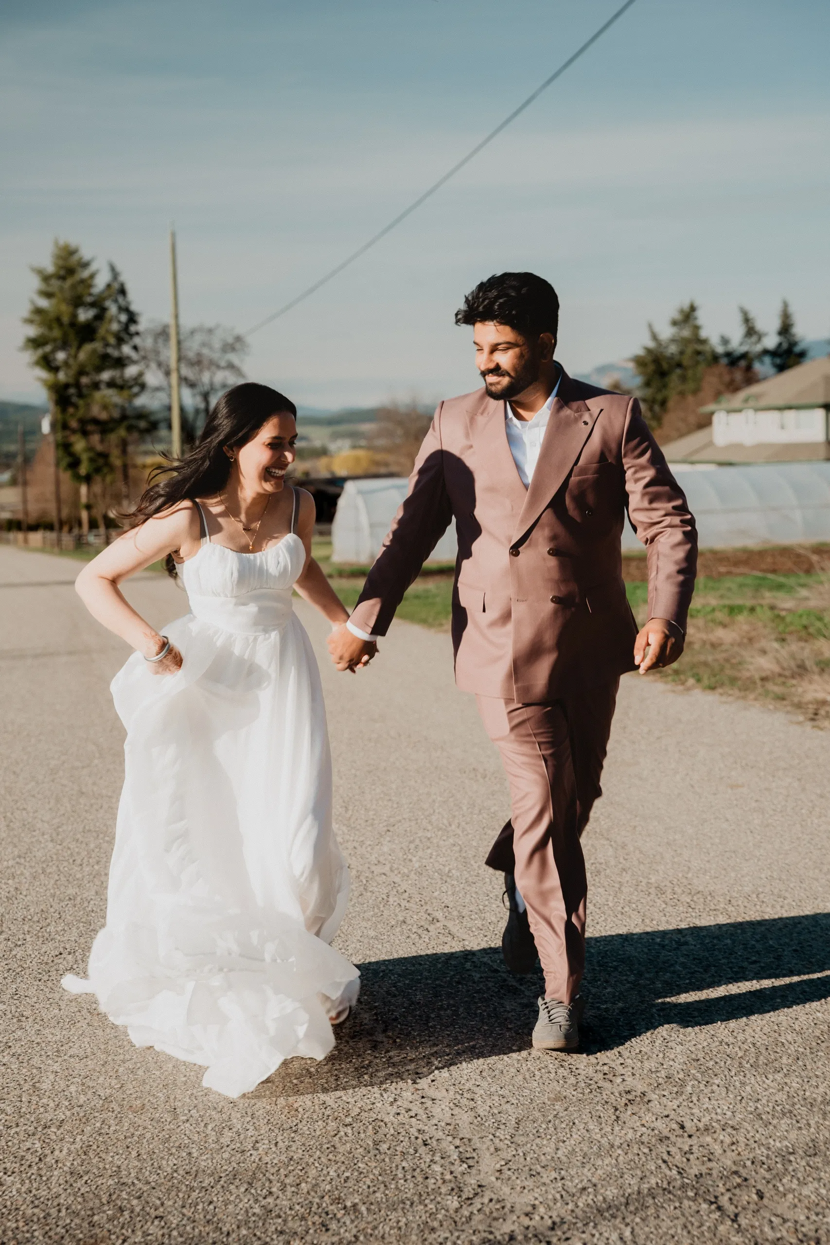 Mehak laughing as they walk hand in hand past a greenhouse in the valley, by AD Photography