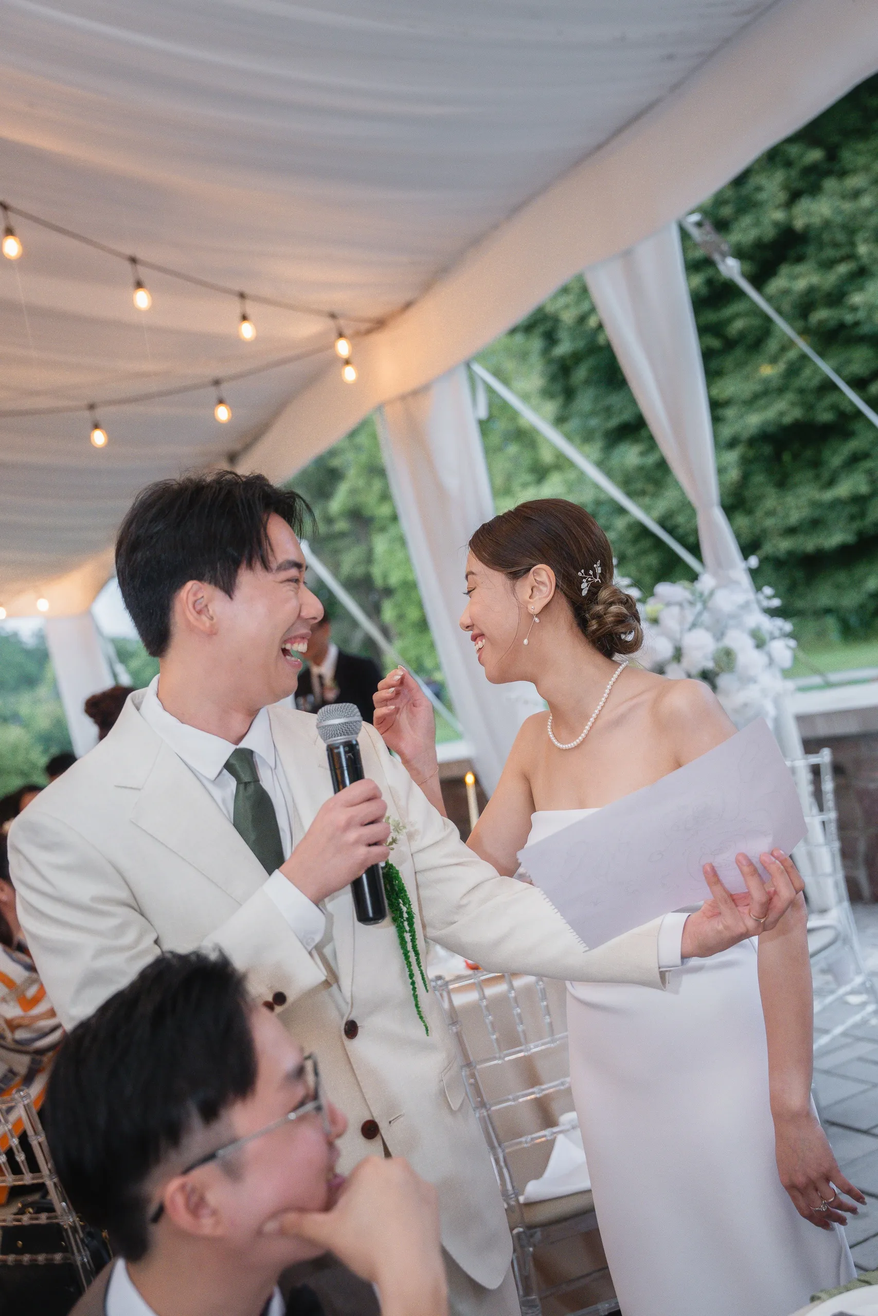 Nelson on the microphone while Josie laughs with her speech pages during the toasts, by AD Photography