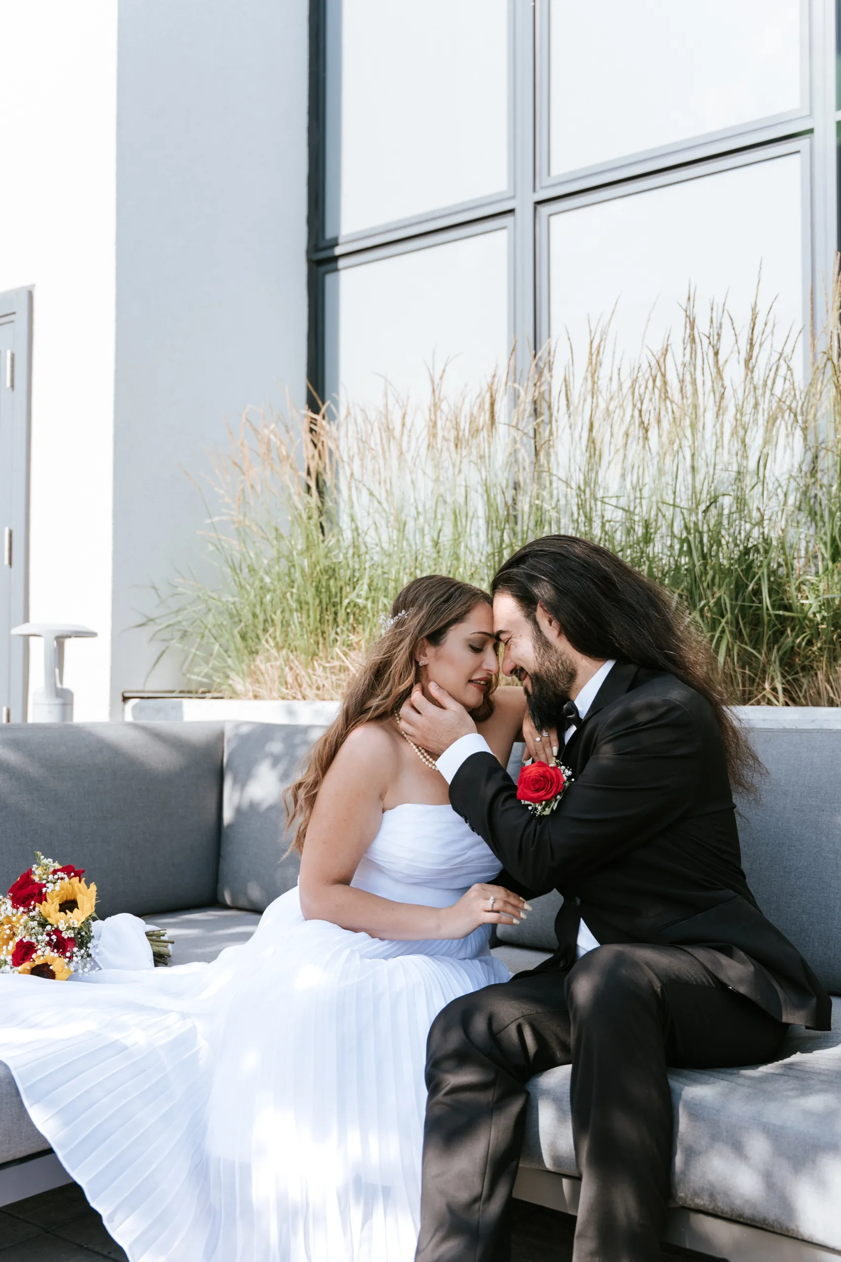 Zoha and Moe put their foreheads together on the terrace couch, her bouquet beside them, by AD Photography