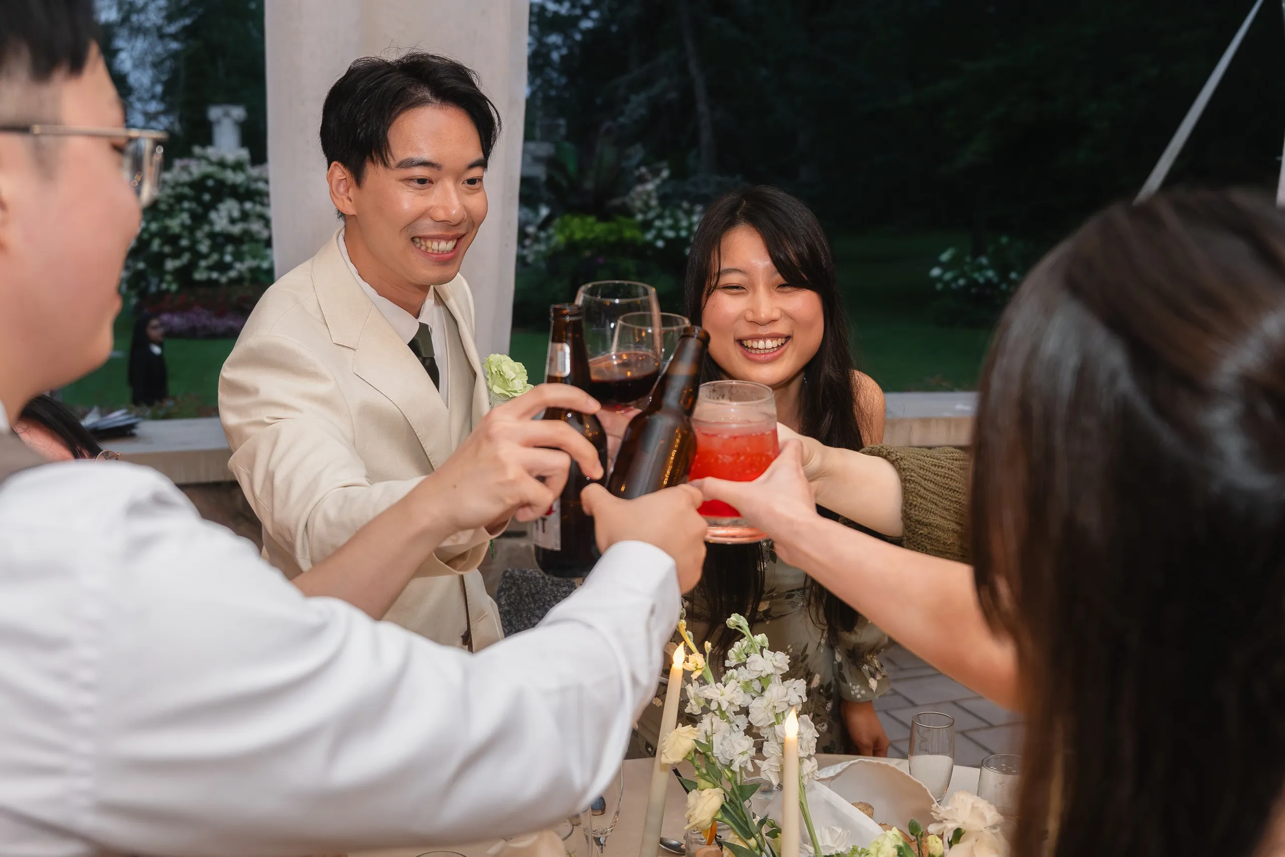 Bottles and glasses clinking over candlelight as Nelson and guests toast in the Guild Park gardens, by AD Photography