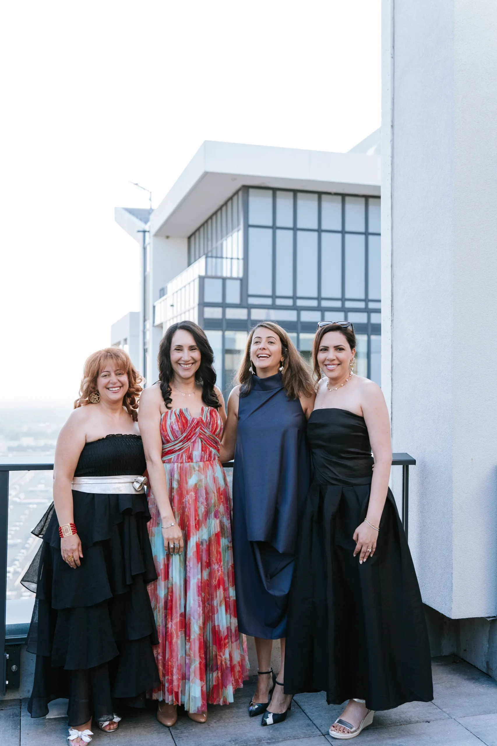 Four women pose together on the terrace with the Maple skyline behind them, by AD Photography