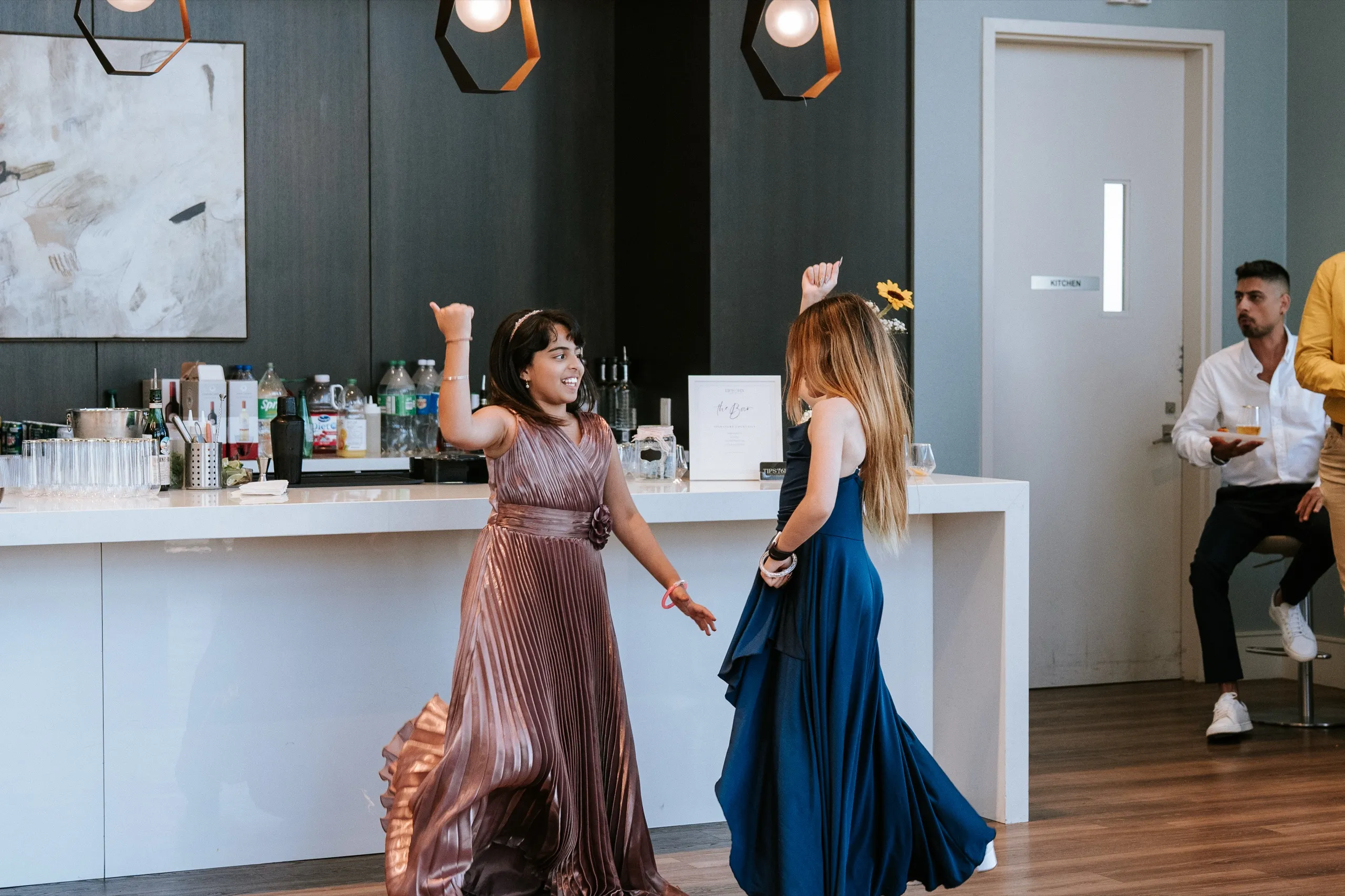 Two guests spin near the bar, their long skirts blurring with the movement, by AD Photography
