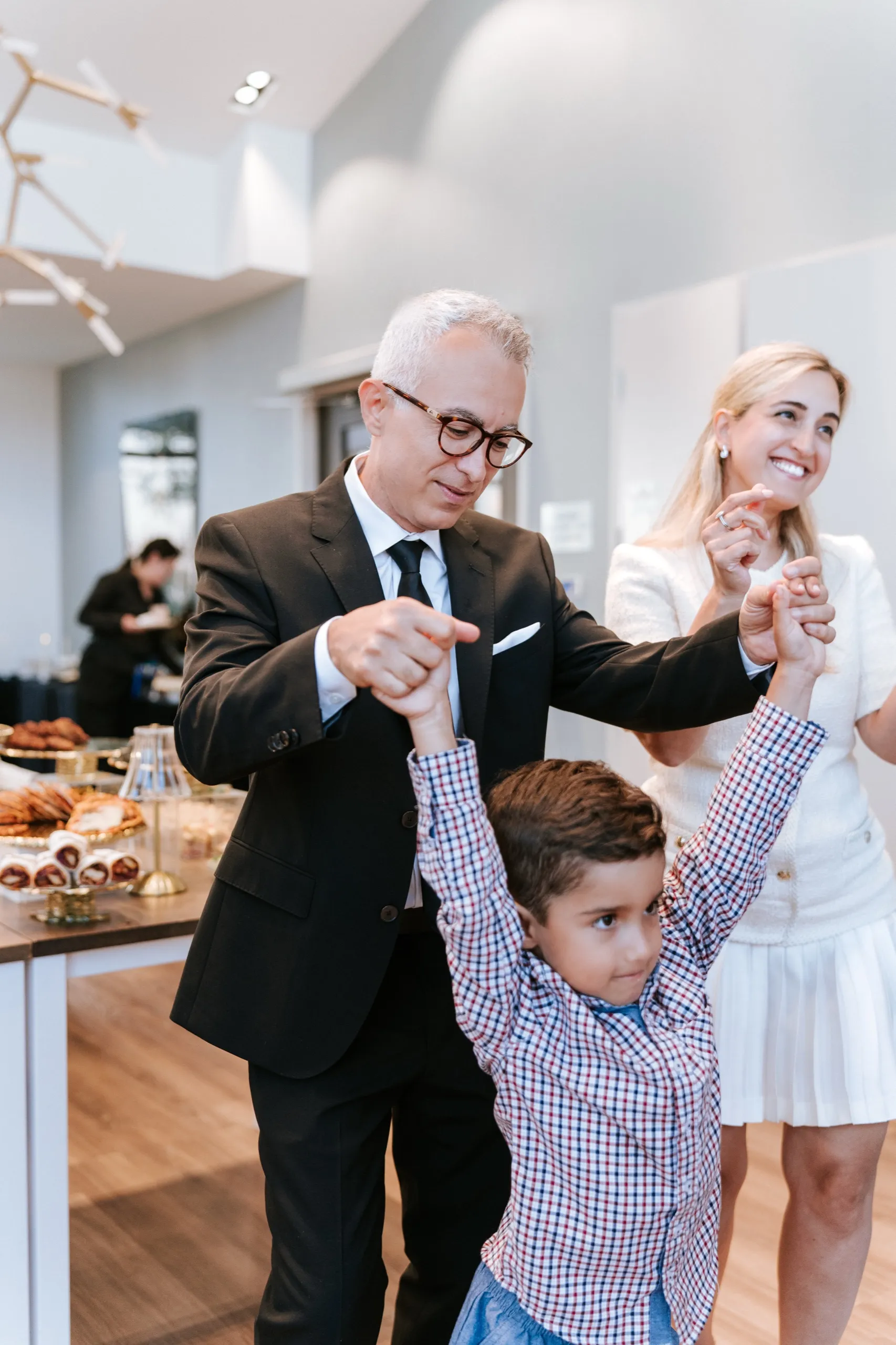 An older guest swings a small boy's arms up high in the middle of the dancing, by AD Photography