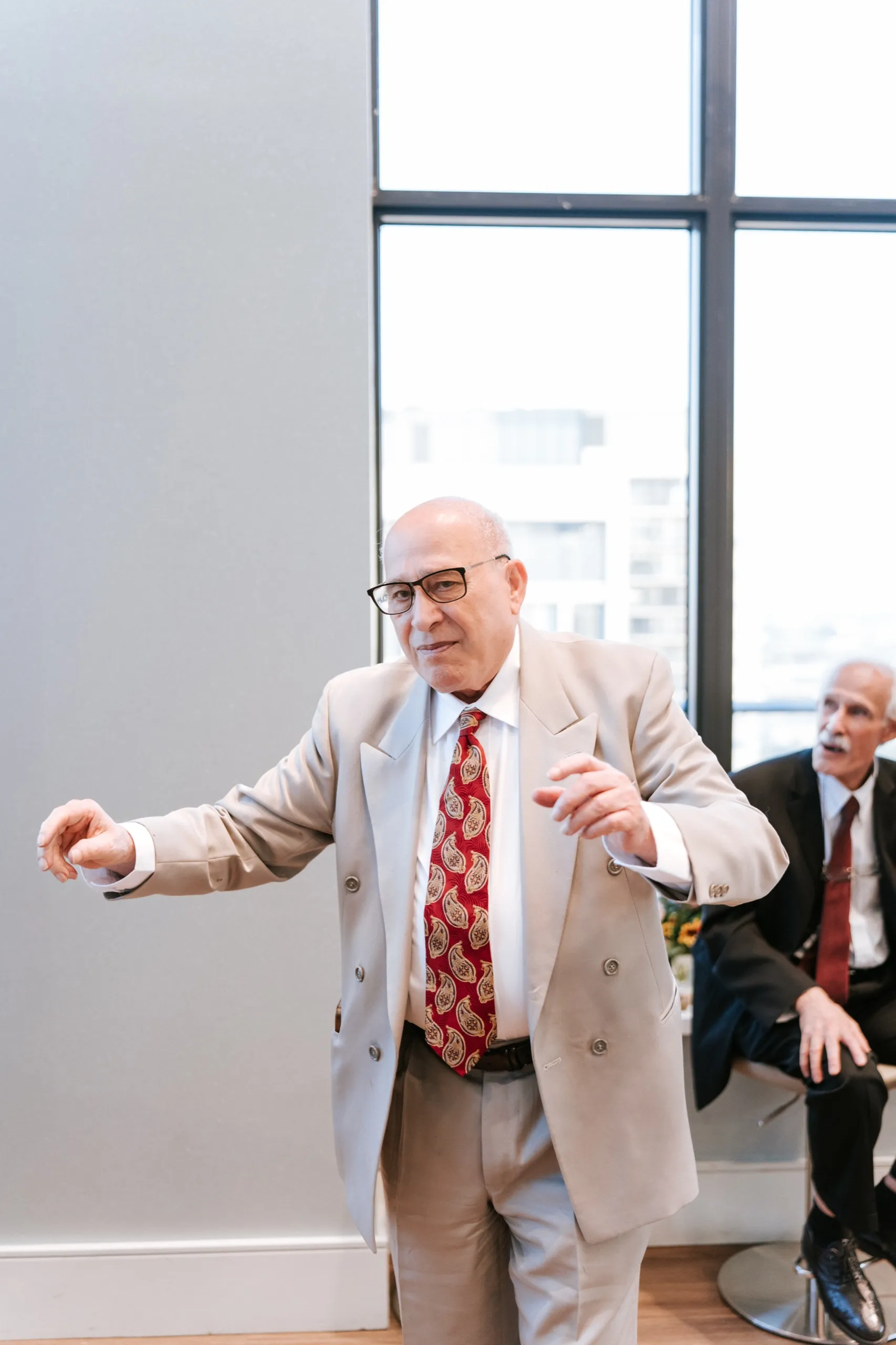 A family elder in a tan suit takes the floor on his own, mid step, by AD Photography
