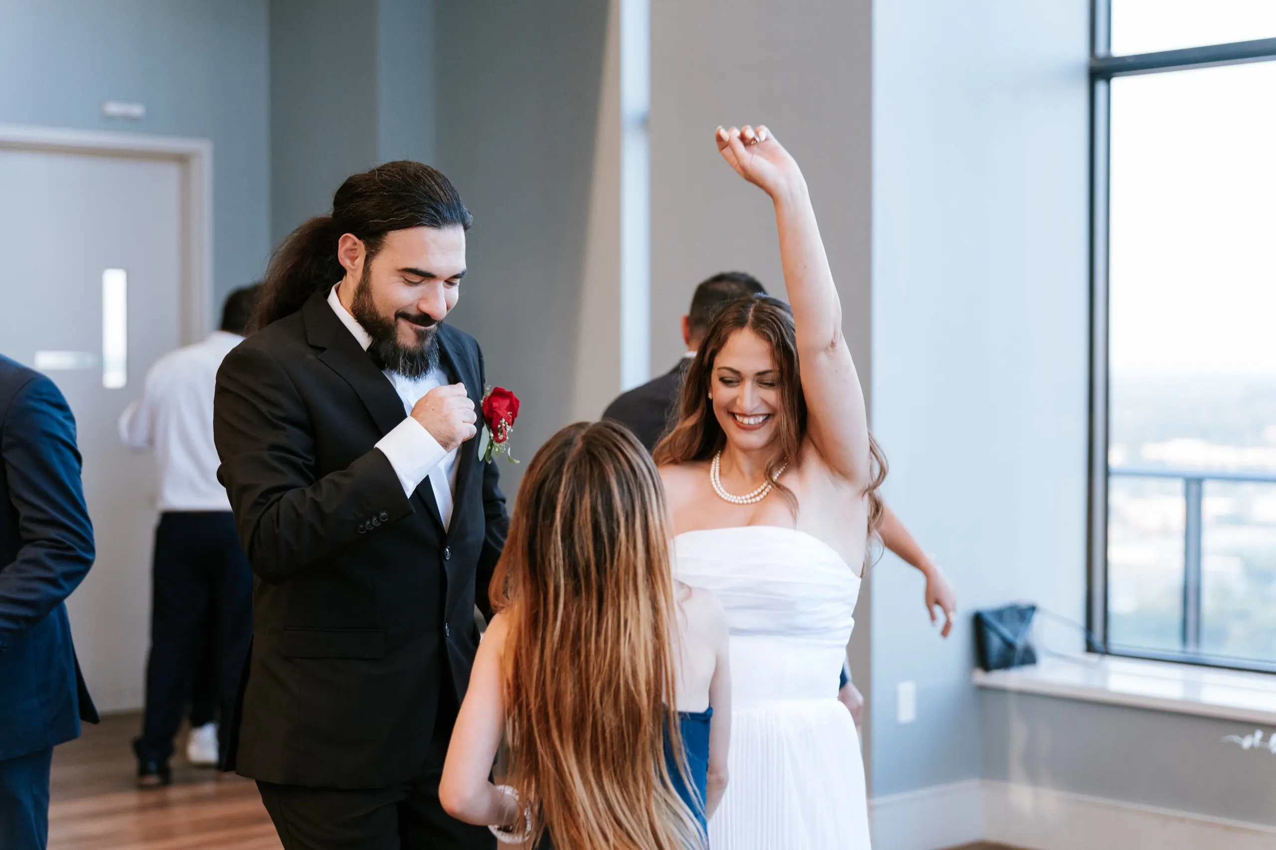 Zoha dances with her arm raised while Moe straightens his rose boutonniere beside her, by AD Photography