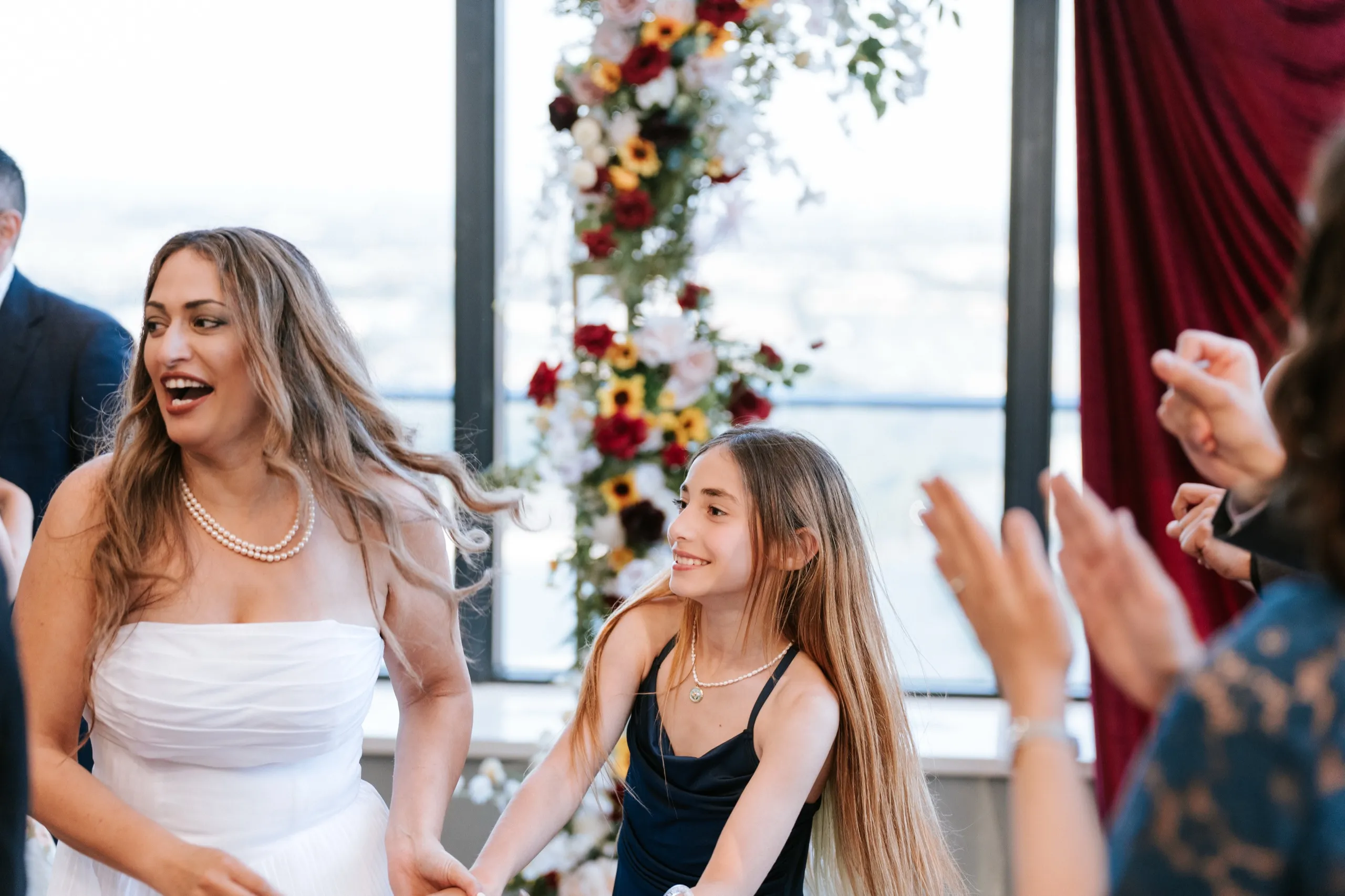 Zoha holds hands with a young girl mid dance while the circle claps them on, by AD Photography
