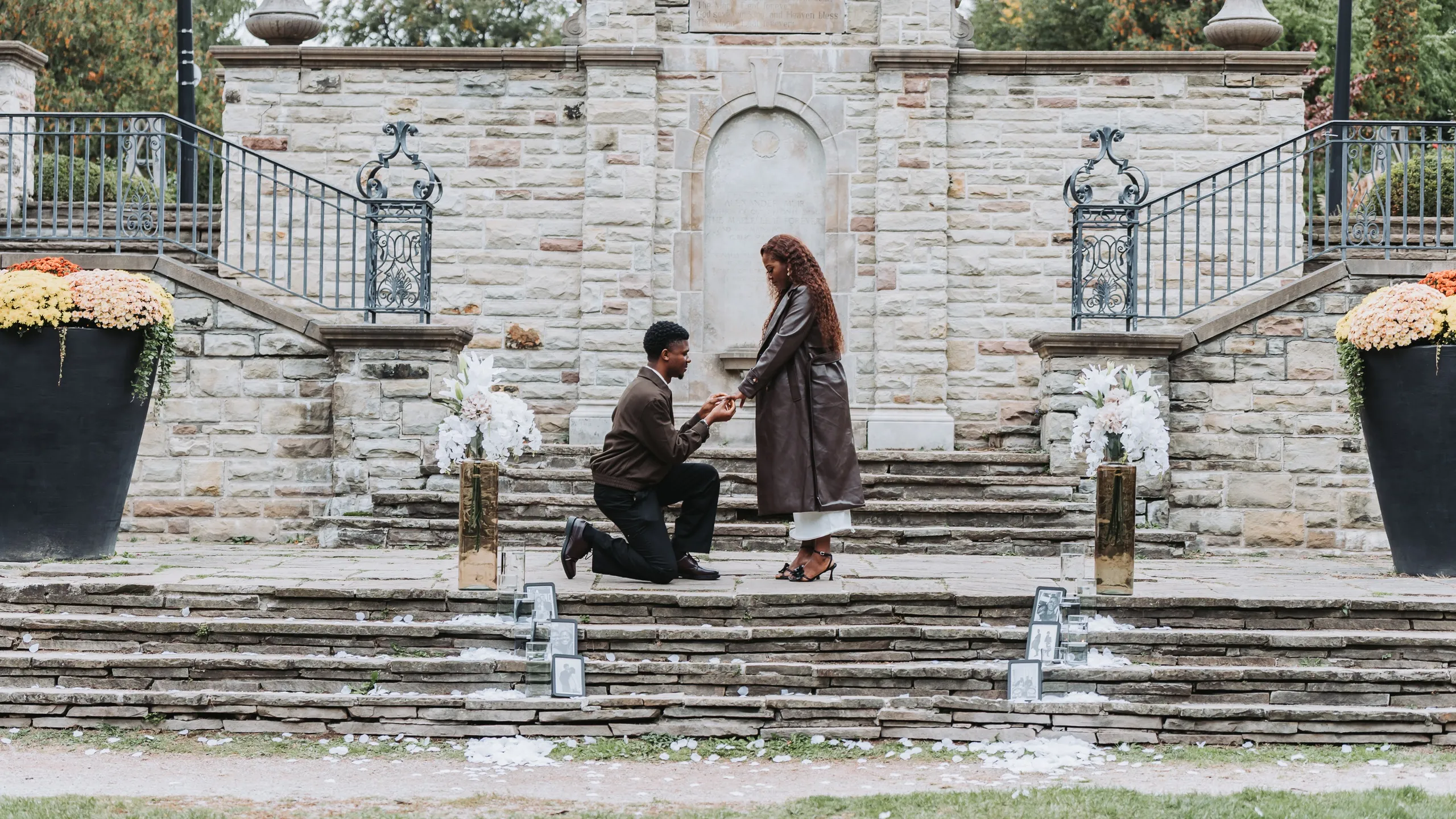 Richie on one knee proposing to Aimee on the stone terrace steps at Alexander Muir Memorial Gardens in Toronto, by AD Photography