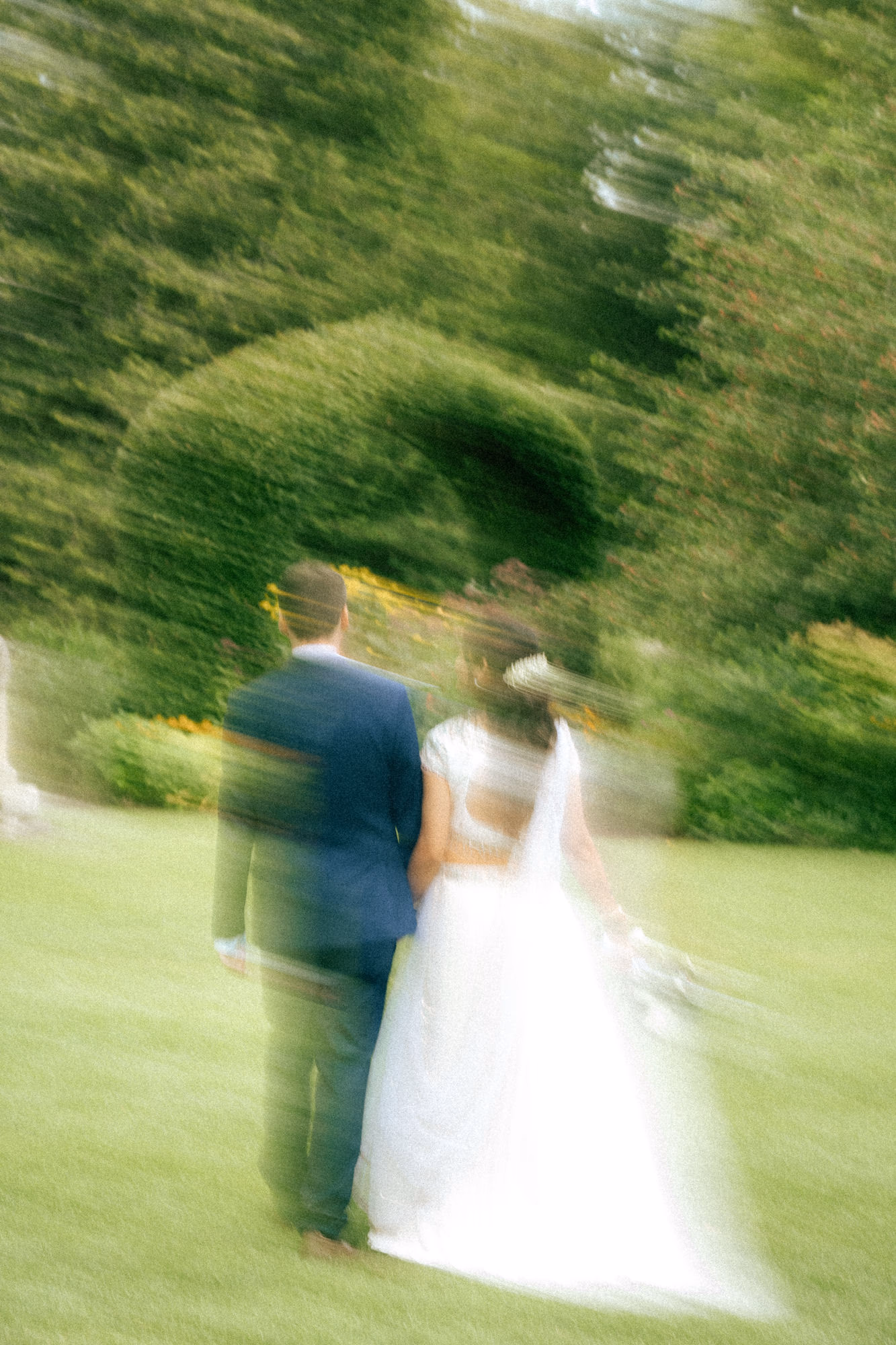 Nidhi and Derek walking away across the lawn at Guild Park in motion blur, Toronto civil ceremony by AD Photography